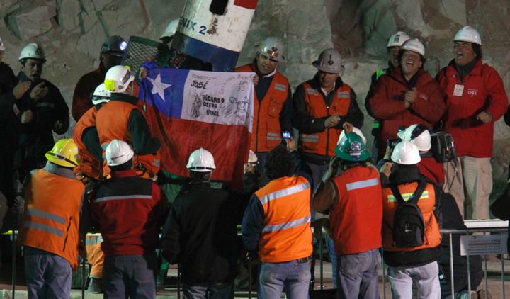 Rescued miner Jose Ojeda holds up a Chilean flag after emerging from the capsule that brought him to the surface
