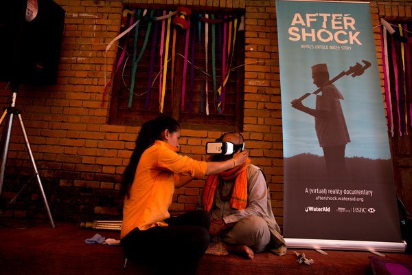 Volunteer, Ganga Sunuwar (left), helping one of the elderly community members to watch the VR film