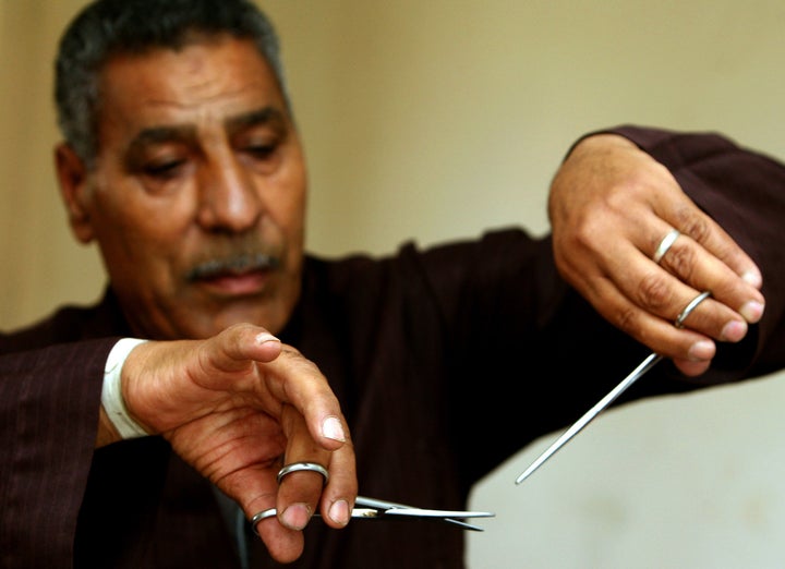 Hassan Hafez, a barber, mimics the way he used to perform female genital mutilation (FGM) in Egypt, June 13, 2006. Becau