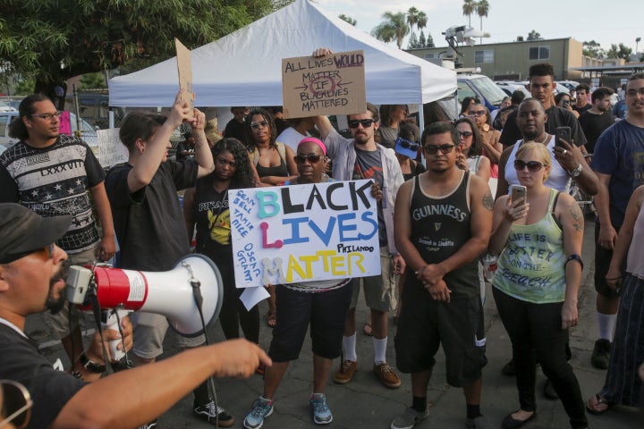 A man speaks through a bull horn as demonstrators assemble in El Cajon.