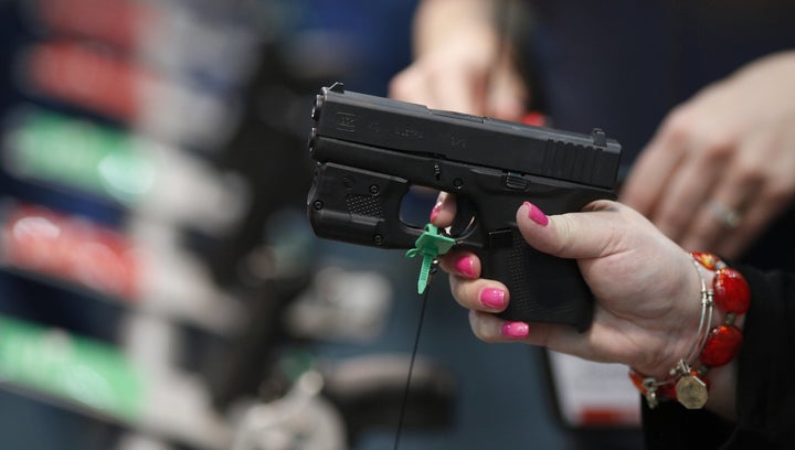 An attendee handles a firearm on the exhibit floor during the National Rifle Association annual meeting in Louisville, Kentuc
