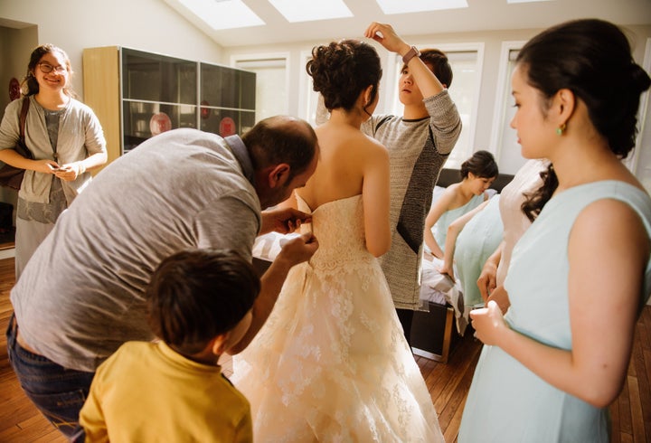 Dudu works at repairing the bride's zipper.