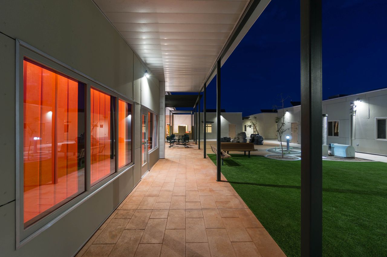 A sheltered patio in the Las Abuelitas Kinship Housing development in South Tucson, Arizona, protects the residents from the sun and elements, while central seating in the common green allows older residents to gather near the children’s play areas.