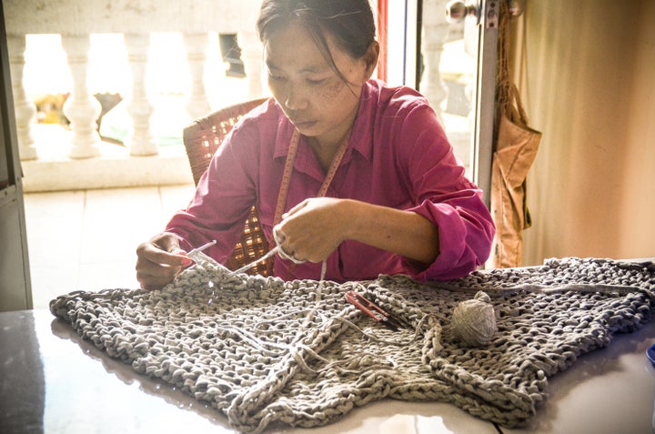 Tonlé employee Ming Eng hand-knits fabric yarn into a cardigan.