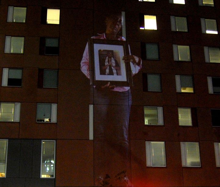 A projection of a mother holding a picture of her slain son on the Boston Police Department building. 