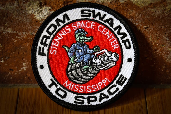 A gift shop at Stennis Space Center in southern Mississippi sells patches showing an alligator sitting atop an RS-25 space shuttle main engine. The RS-25 will now be used to power the Space Launch System. Stennis has been the home of NASA rocket engine testing since the Apollo program.