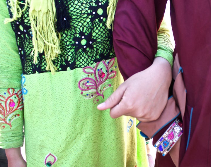 Teenage Iraqi girls stand, arm in arm, wearing brightly colored, intricately adorned clothing banned under ISIS rule.