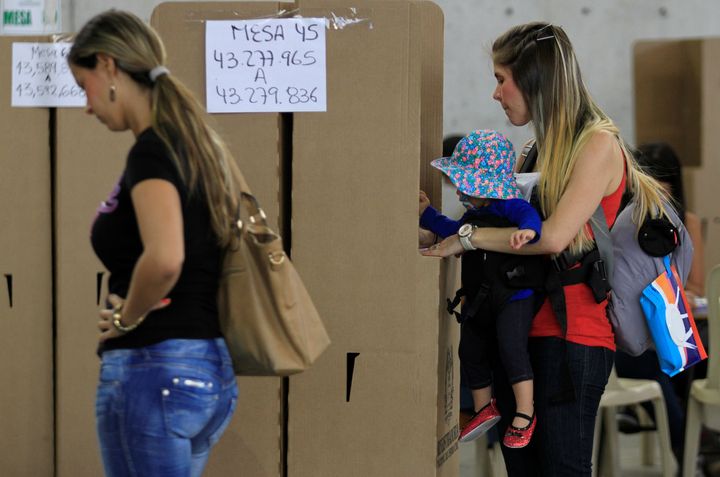 A woman carrying her daughter casts her vote in a referendum on a peace deal between the government and Revolutionary Armed Forces of Colombia (FARC) rebels in Medellin, Colombia, October 2, 2016. (REUTERS/Fredy Builes)