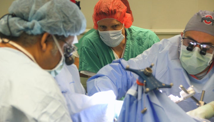 Dr. Ali Rezai, right, implants a tiny chip into the brain of a patient. Rezai and dozens of researchers have pioneered neural bridging technology, which links the chip in a patient's brain to a high-tech sleeve placed onto the the forearm. For the first time ever, the technology recently allowed a patient to move his paralyzed arm using his own thoughts.