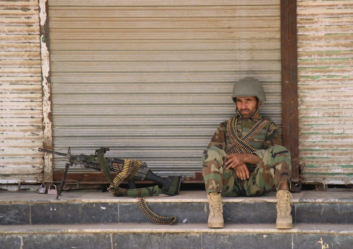 An Afghan National Army (ANA) soldier sits in front of a closed shop in the downtown of Kunduz city, Afghanistan October 3, 2016.