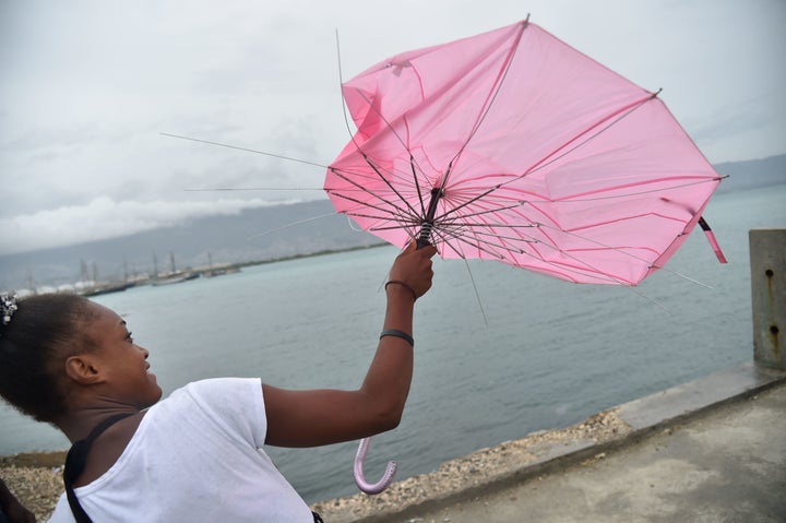 A girl tries to repair her umbrella that was broken by the wind in the commune of Cite Soleil in the Haitian capital of Port-