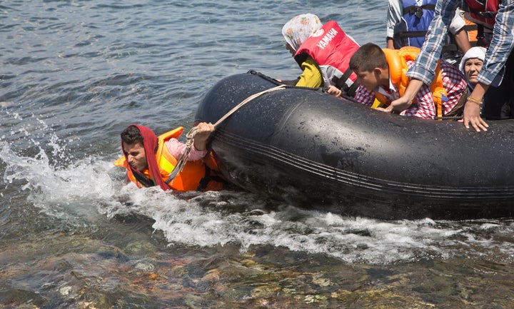 A Syrian migrant pulls a rubber boat towards the shore of Eftalou beach, Greece, in August 