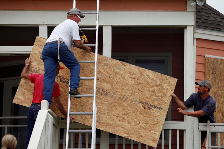 Allen Scurry (L), Brent Scurry (C) and Brandon Floyd, all of Lake City, South Carolina, install window shutters at an ocean f