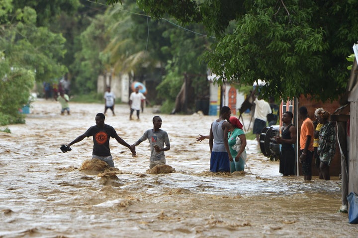 People try to cross the overflowing La Rouyonne river in the commune of Leogane, south of Port-au-Prince, Haiti, on Oct. 5.