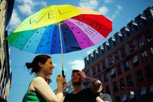 Protesters hold an umbrella with "Refugees Welcome" written on it in Berlin on May 7, 2016.