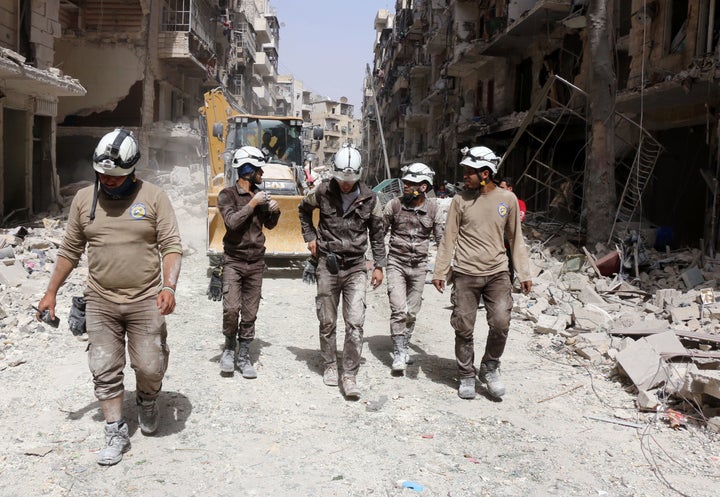 Members of the White Helmets walk amid the debris following a reported airstrike by Syrian government forces in Aleppo on June 3.