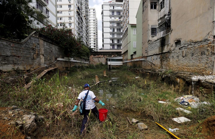 A health agent carries a bucket of guppy fish to place them in standing water to consume larva of Zika-transmitting mosquitoes in an empty lot of Rio de Janeiro's Tijuca neighborhood, Brazil, February 17, 2016.