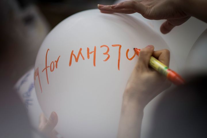 A family member of a victim of MH370 writes a message on a balloon during a memorial event in Malaysia 
