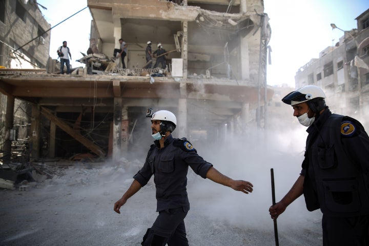 <strong>Syrian civil defence volunteers, known as the White Helmets, work around destroyed buildings following reported air strikes.</strong>