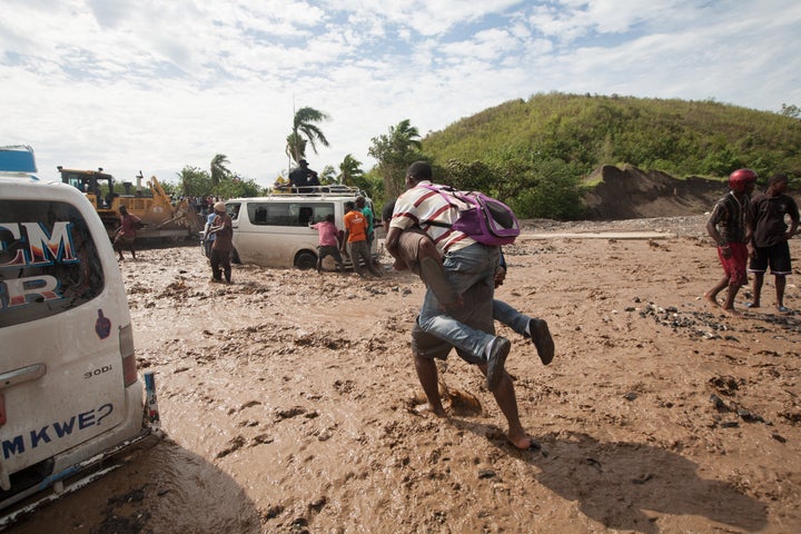 People trying to walk or drive through a river in Haiti after a nearby bridge collapsed because of the hurricane.