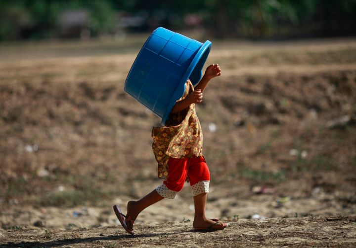 A girl carries an empty bucket over her head to collect water at Yazarthingyan lake in Dala township, near Yangon May 12, 2013.