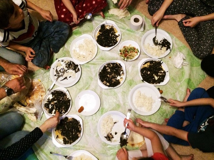 Inside their shelter room, sisters Toulin and Yasmin gather with their family for a dinner of rice and molokhia, a vegetable dish popular in the Middle East.