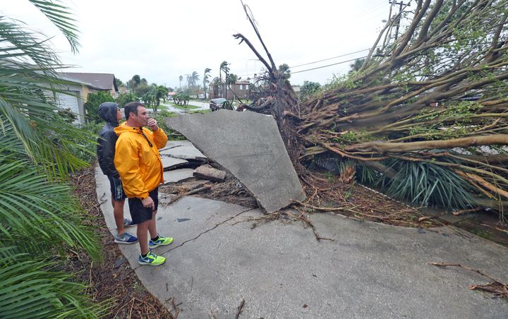 Rob Napier, 48, right, and his son Robbie,20, of Merritt Island survey an uprooted tree in a neighbors yard a casualty Thursday, October 7, 2016 of Hurricane Matthew as the Category 4 storm brushed the Florida east coast.