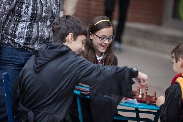 Young visitors play a game of chess in their wizard cloaks.