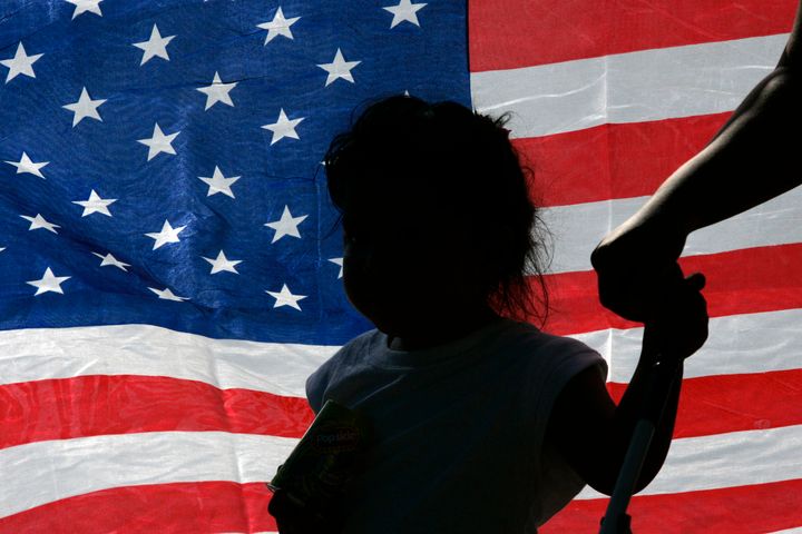A child is silhouetted against a U.S. flag at a rally in support of immigration rights in Irving, Texas October 13, 2007.