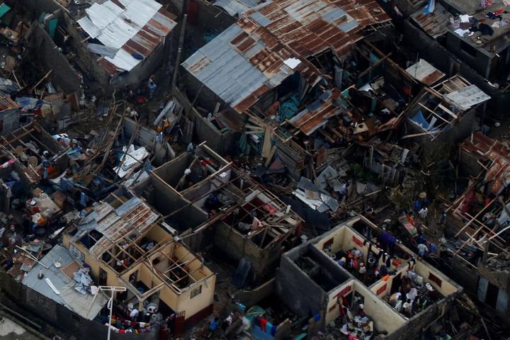 People walk next to destroyed houses after Hurricane Matthew passes Jeremie, Haiti.