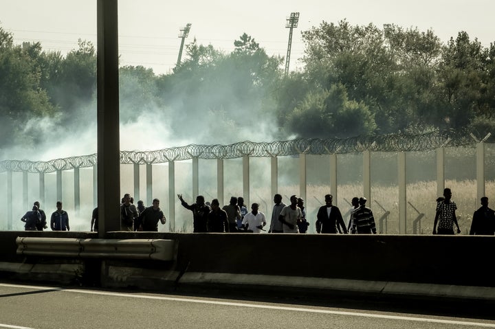 Migrants run away from tear gas during clashes with riot police trying to prevent them from getting into trucks heading to Great Britain, on September 21