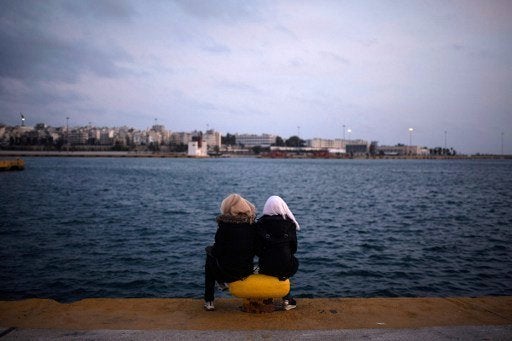 Two women from Syria sit facing the sea in Athens in March 2016.