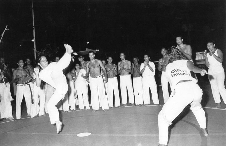 Professora Pimentinha (left) playing in a Capoeira roda with Ginga Mundo Mestre Sabia (center) looking in Bahia, Brazil.