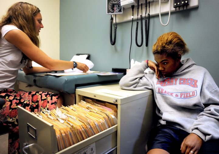 Dr. Jenni Burns, left, looks over paper work as LeeLee Hanley, 19, keep a close eye on her pregnancy test at Urban Peak, a homeless shelter for teens.