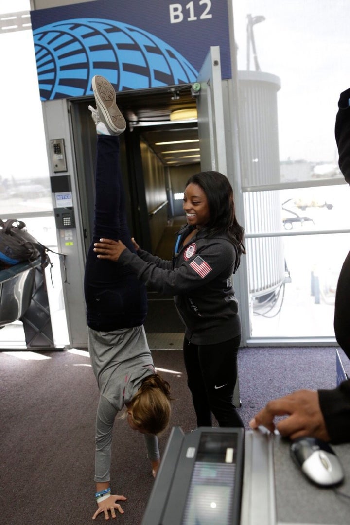 Simone Biles helps a passenger into a handstand at O'Hare International Airport.