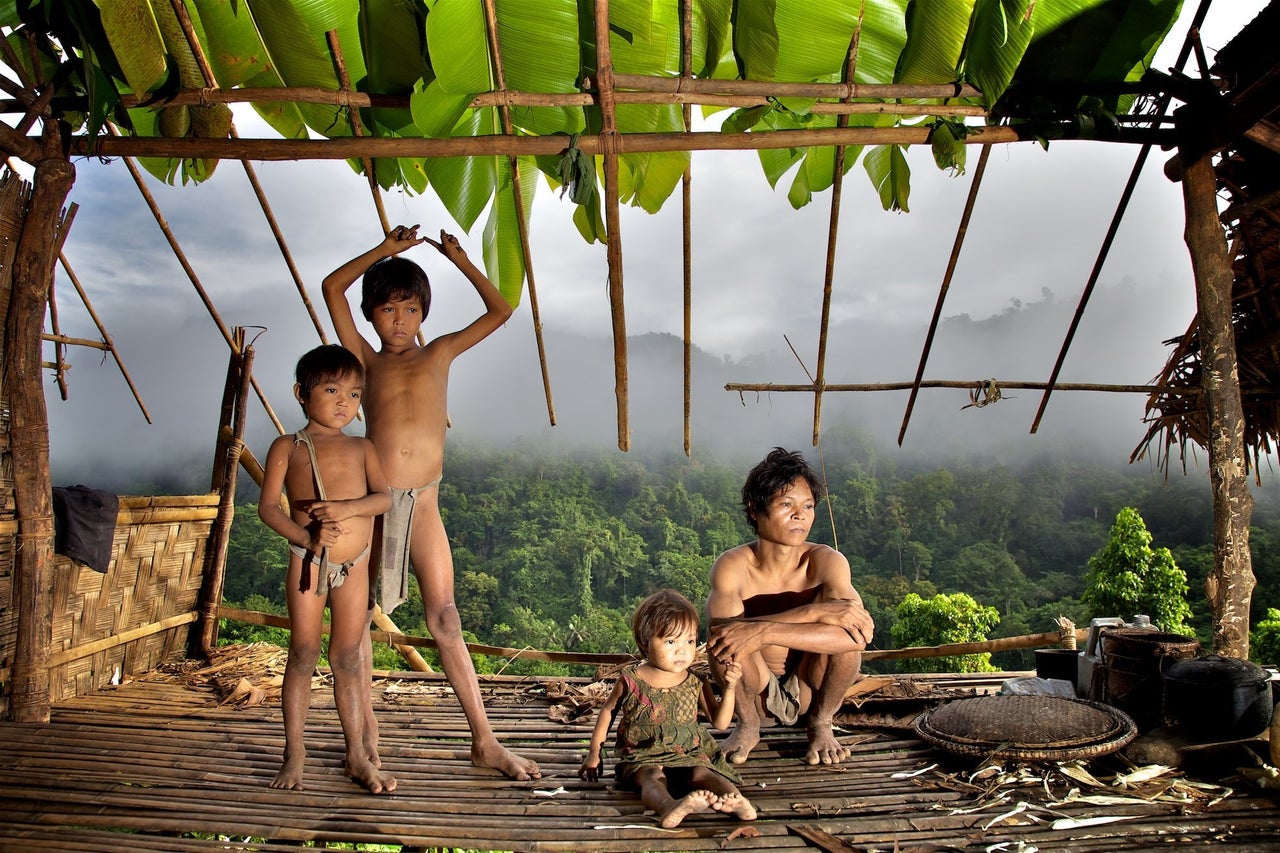 A father and daughter look down over the Singapan Valley from their house. Taut Batu tribe, Palawan, Philippines.