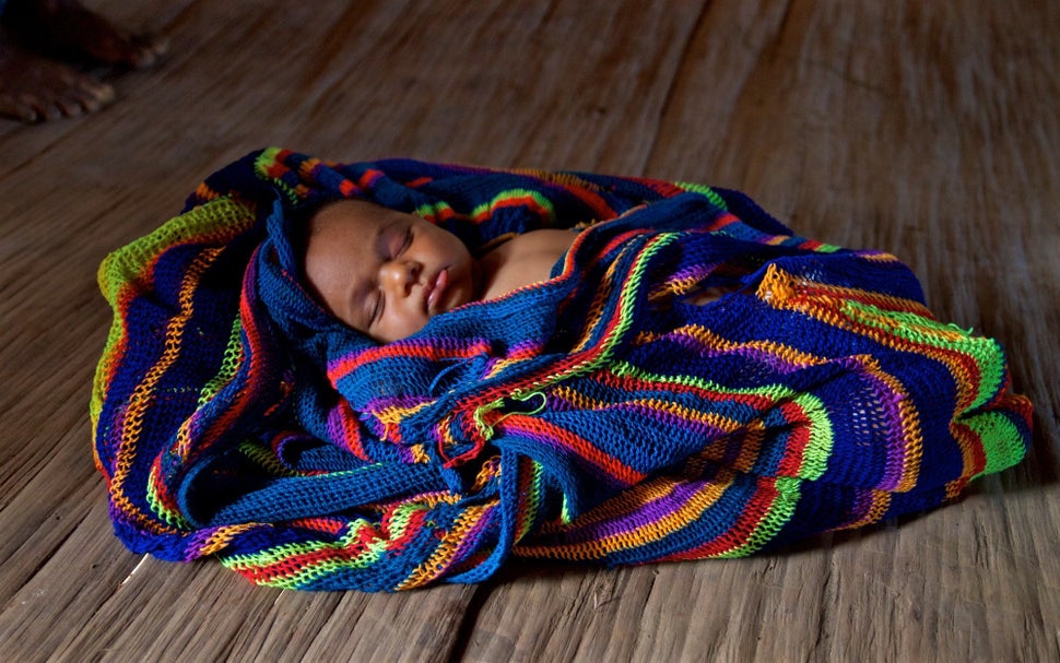 Sibilato’s newborn daughter sleeps in a traditional woven bilum. Bosavi region, Southern highlands, Papua New