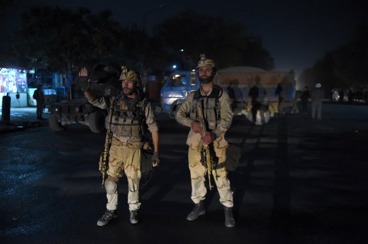 Afghan security personnels stands as they keep watch near the site of an attack by gunmen inside the Kart-e- Sakhi shrine in