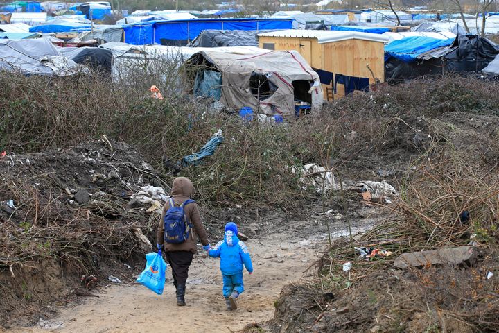 A migrant and her child walk in the Calais camp 
