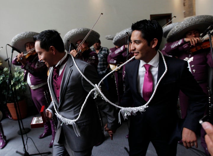 Newlyweds Diego, right, and Ricardo leave their wedding ceremony as a mariachi band plays on July 14, 2013 in Mexico City.