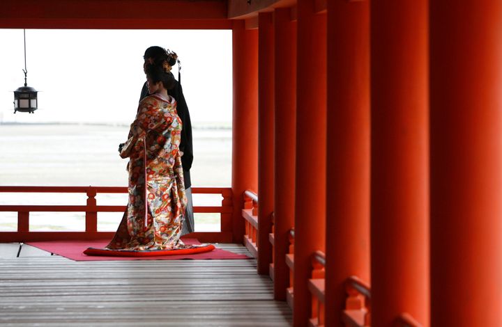 A bride and groom in traditional Japanese wedding attire pose for photos at Itsukushima Shrine in Hatsukaichi, Japan, on April 16, 2008.
