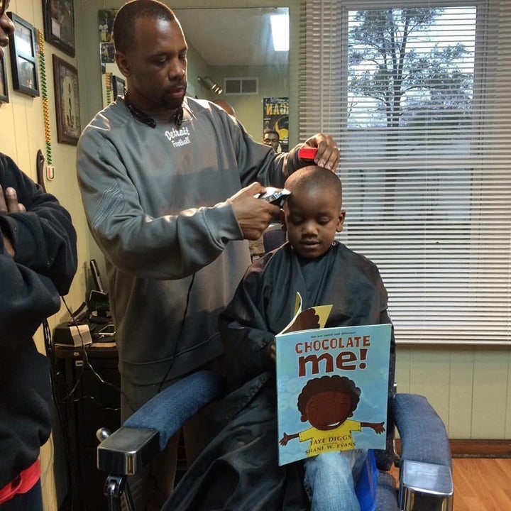 Ryan Griffin cutting a boy’s hair while he reads aloud.