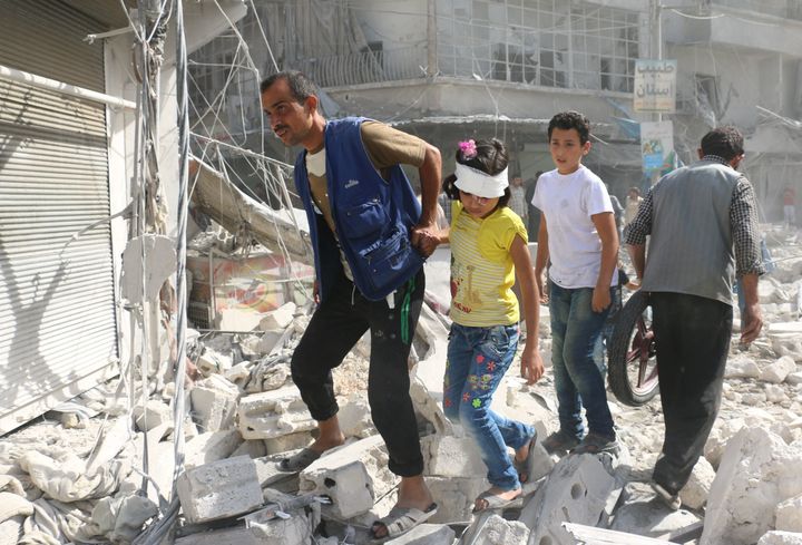 Syrians walk over rubble in Aleppo