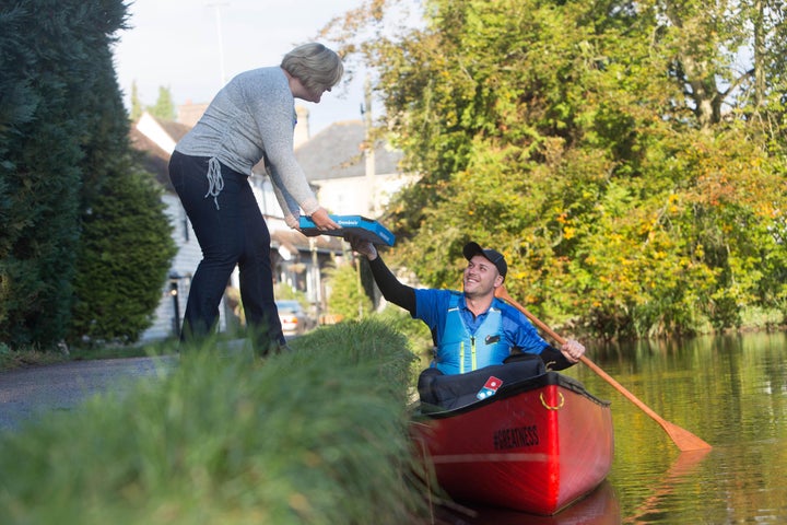 Robert Isuf paddles a canoe down the River Loose to deliver pizza to local woman Debbie Hayes.