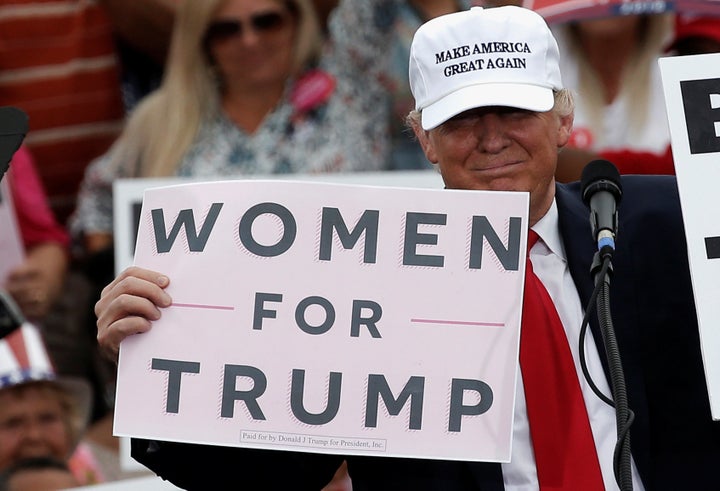 Donald Trump holds up signs at the end of a campaign rally in Lakeland, Florida, U.S., October 12, 2016.