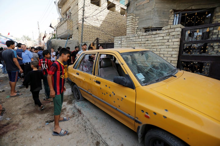 People gather at the site of a suicide bomb attack in the city's northern al-Shaab district in Baghdad, Iraq, Saturday.