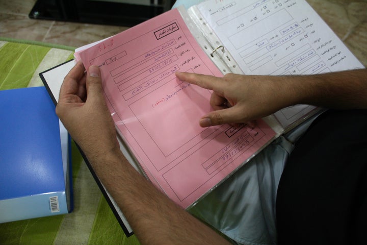 Yazidi activist Bahzad Farhan Murad looks through binders containing information about killed, kidnapped and freed