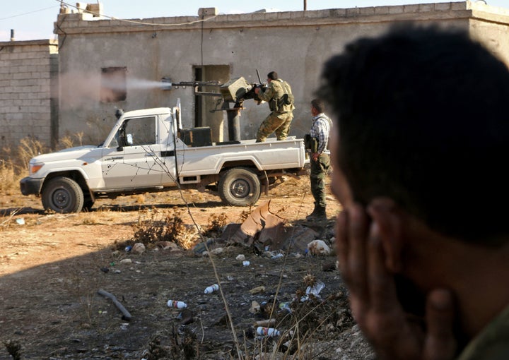 Fighters from the Free Syrian Army fire a machine gun mounted on a vehicle deployed during fighting against the self-describe