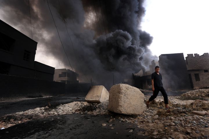 An Iraqi man walks near oil wells set ablaze by Islamic State militants fleeing the oil-producing region of Qayyarah on Aug.&
