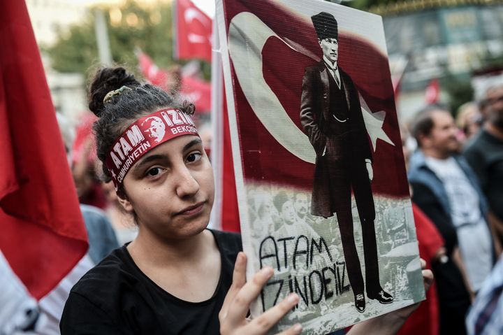 A woman holds a placard picturing Turkisk national flag and Turkey's first president and founder of modern Turkey Mustafa Kemal Ataturk in Istanbul, on August 30, 2016